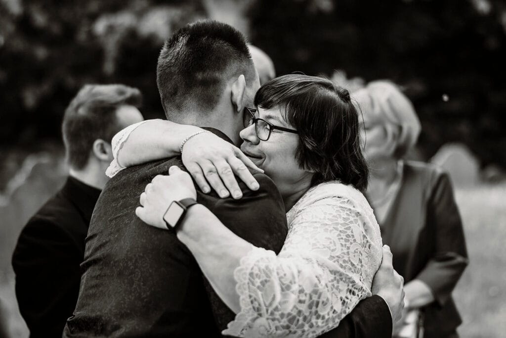 Stiepeler Dorfkirche Landhaus Grum Hattingen Hochzeitsfotograf - Hochzeitsgast umarmt Bräutigam
