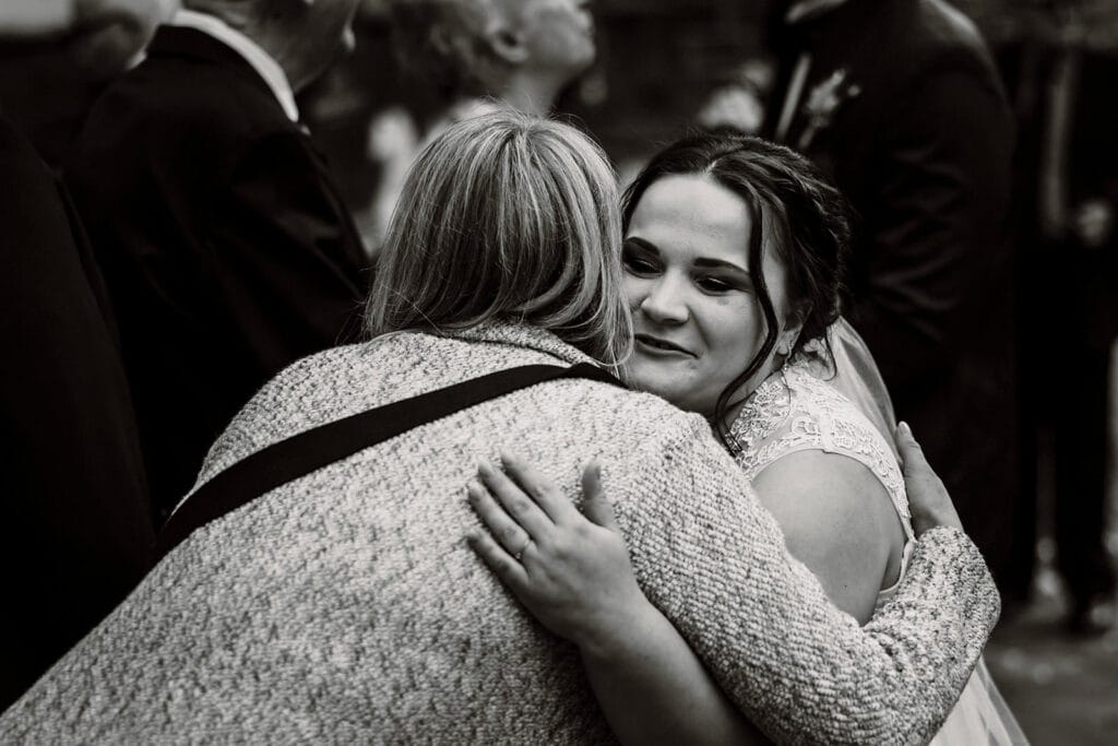 Stiepeler Dorfkirche Landhaus Grum Hattingen Hochzeitsfotograf - Hochzeitsgast umarmt die Braut