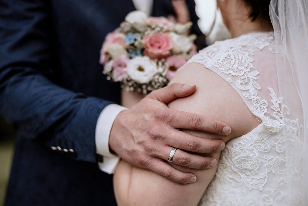 Stiepeler Dorfkirche Landhaus Grum Hattingen Hochzeitsfotograf - Bräutigam hält Arm der Braut fester. zu sehen ist auch der Trauring