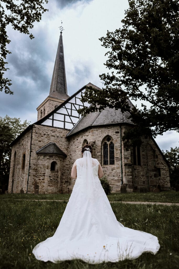 Stiepeler Dorfkirche Landhaus Grum Hattingen Hochzeitsfotograf - Braut steht vor der Kirche Stiepeler Dorfkirche
