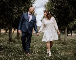 Glessener Mühlenhof Bergheim Hochzeitsfotograf - Hochzeitspaar hält Händchen und geht Baumallee entlang