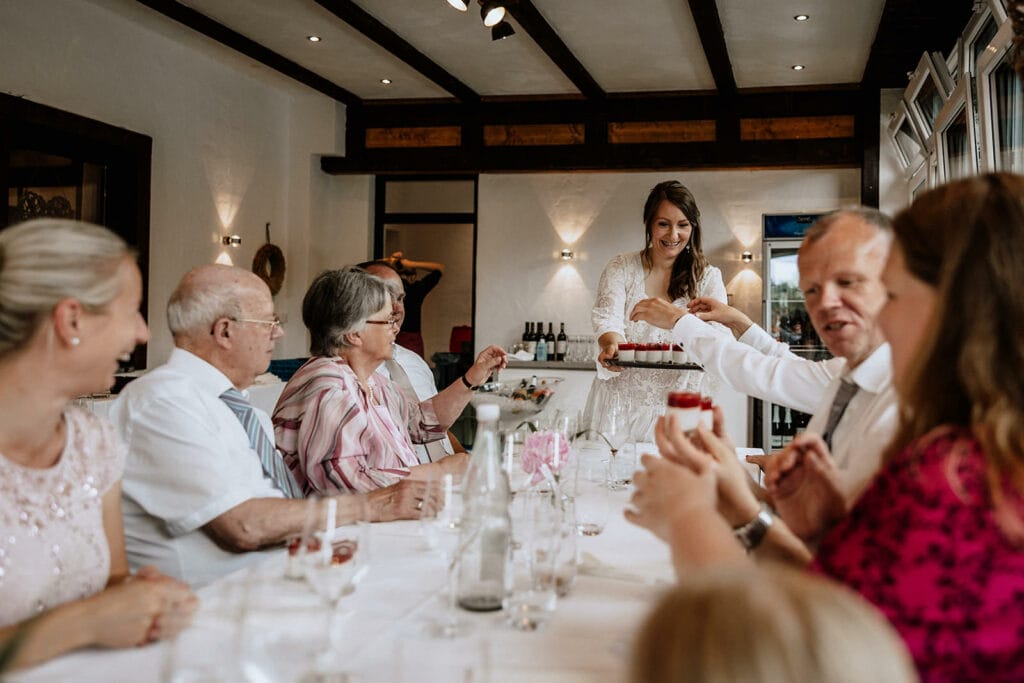 Glessener Mühlenhof Bergheim Hochzeitsfotograf - Braut verteilt Nachtisch an Hochzeitsgäste