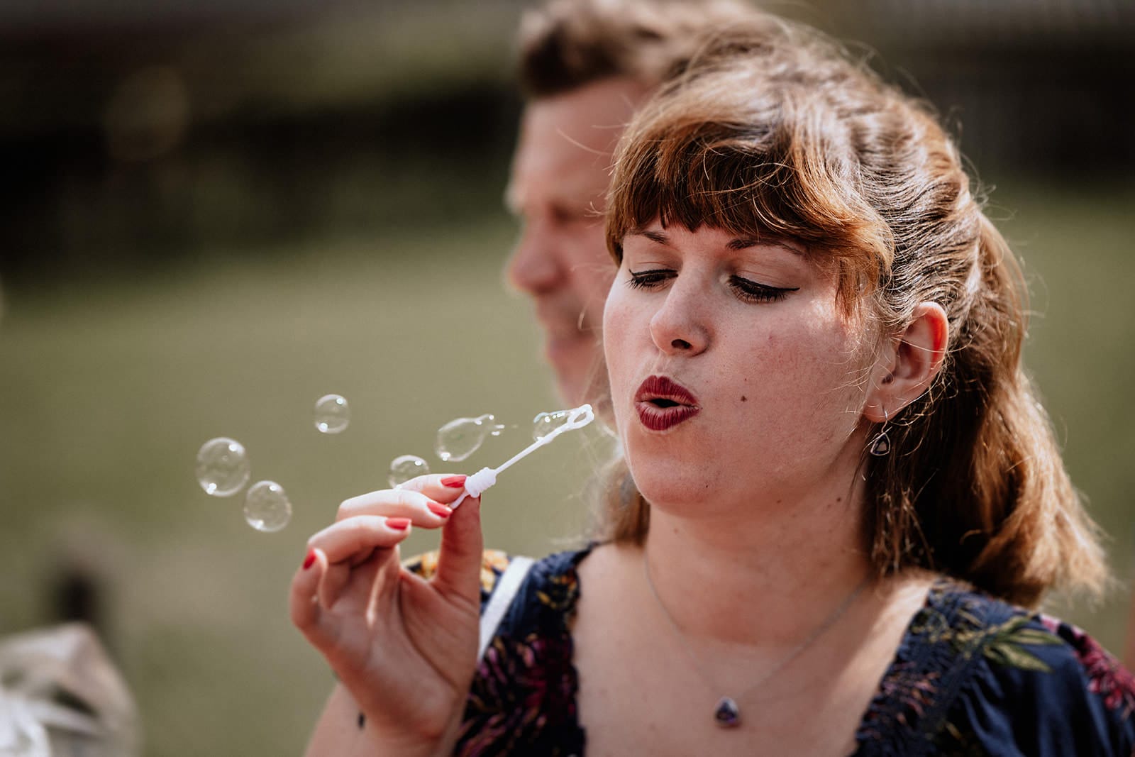Glessener Mühlenhof Bergheim Hochzeitsfotograf - Hochzeitsgast bläst Seifenblasen zur Feier der Trauung