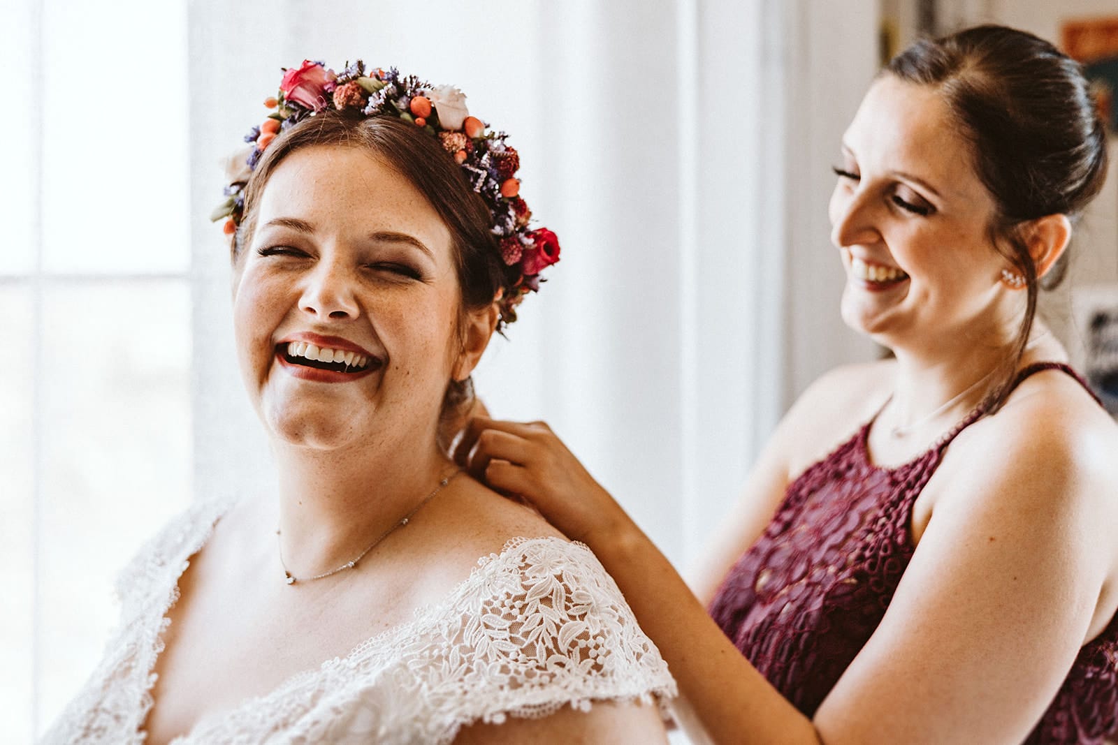 Herrenhaus Cromford Ratingen 25hours Hotel Düsseldorf Hochzeitsfotograf - Trauzeugin hilft Braut am Anziehen der Halskette