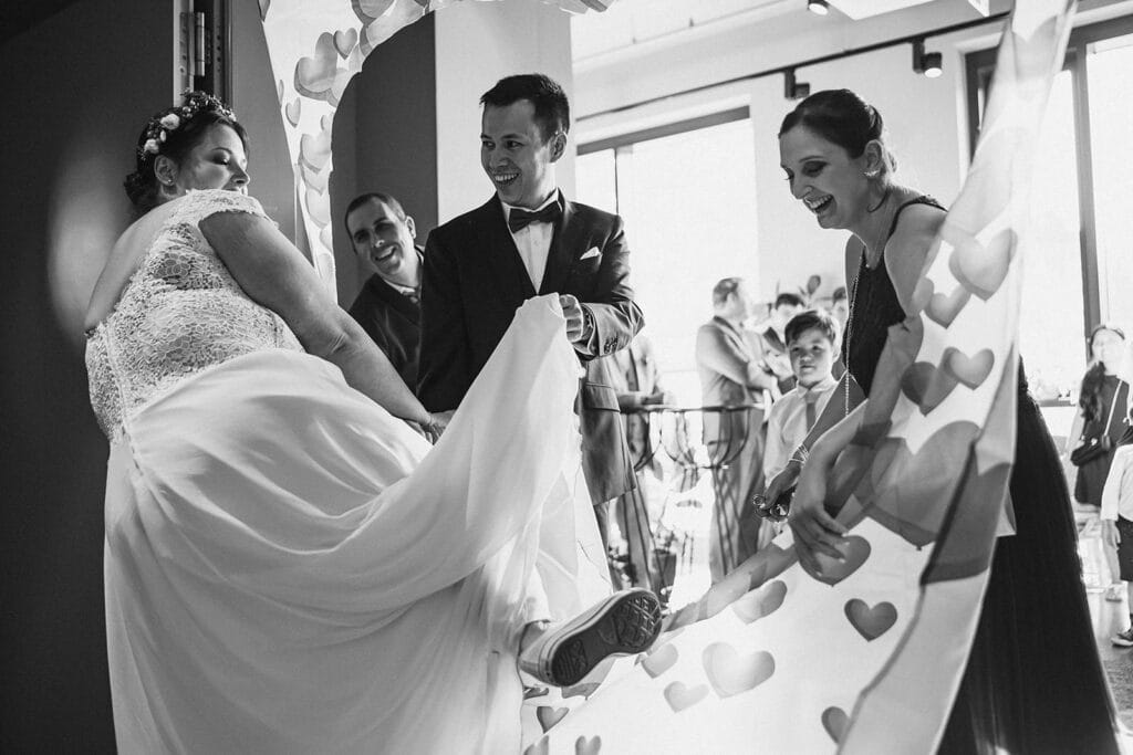 Herrenhaus Cromford Ratingen 25hours Hotel Düsseldorf Hochzeitsfotograf - Bräutigam verhilft Braut durch den Stoff