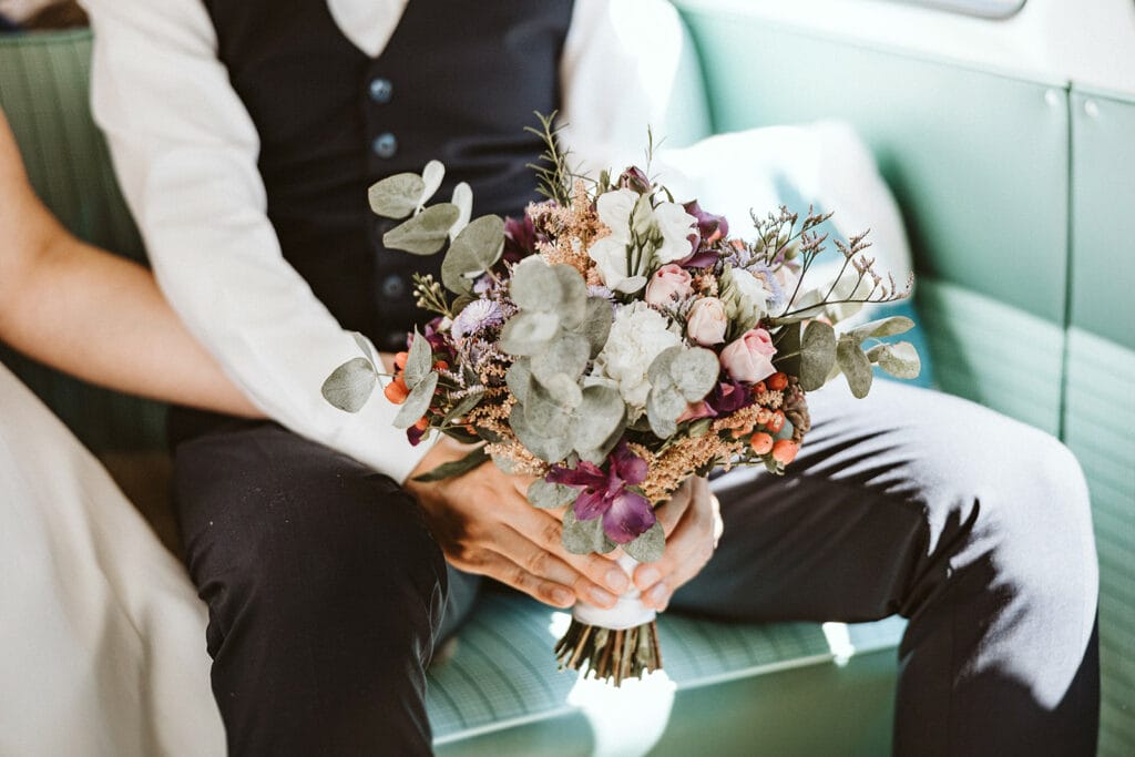 Herrenhaus Cromford Ratingen 25hours Hotel Düsseldorf Hochzeitsfotograf - Bräutigam hält Strauß im VW Bulli