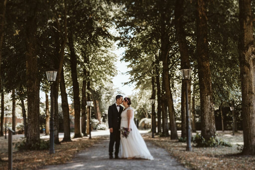 Herrenhaus Cromford Ratingen 25hours Hotel Düsseldorf Hochzeitsfotograf - Hochzeitspaar vor Baumallee