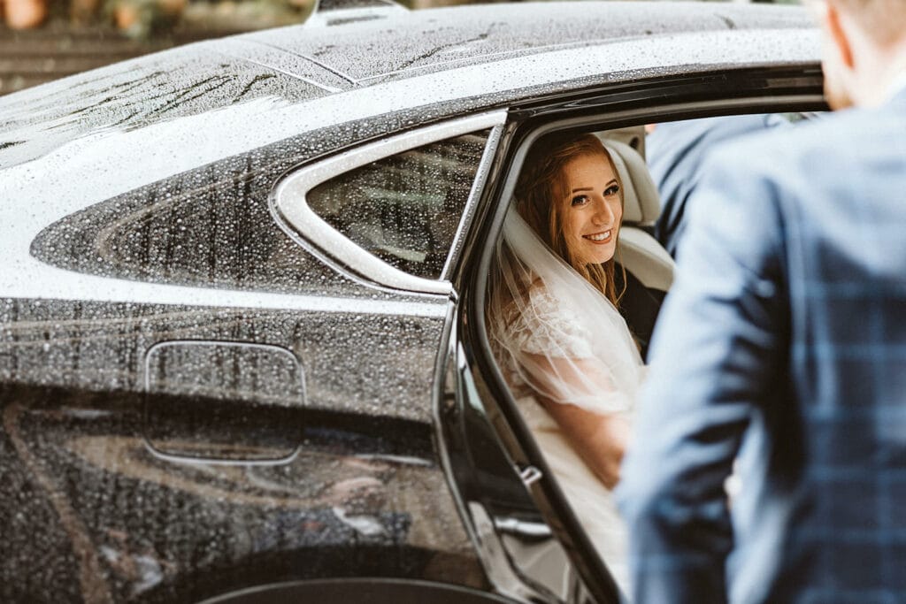 St. Lambertus Mettmann Trüffelschwein Hilden Hochzeitsfotograf - Braut steigt aus verregnetem Auto