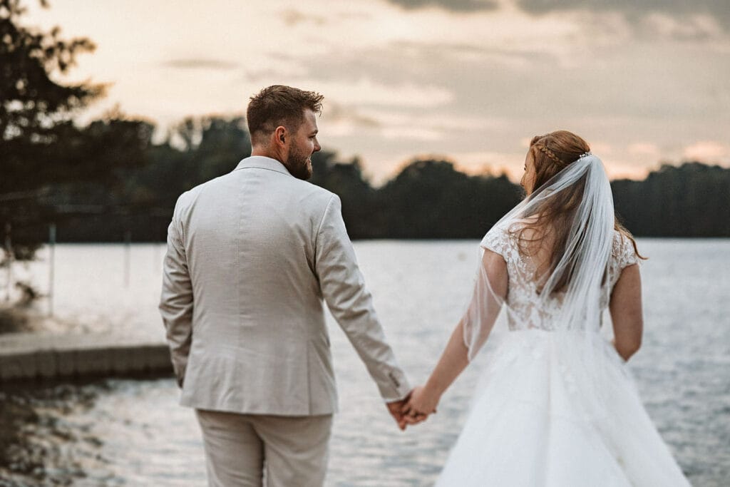 St. Lambertus Mettmann Trüffelschwein Hilden Hochzeitsfotograf - Braut und Bräutigam schauen zum See und halte Händchen