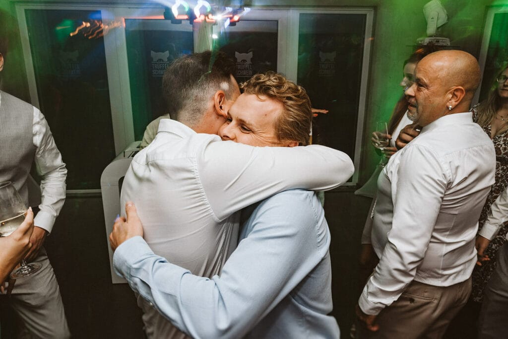St. Lambertus Mettmann Trüffelschwein Hilden Hochzeitsfotograf - Zwei Männer umarmen sich auf Hochzeitsparty