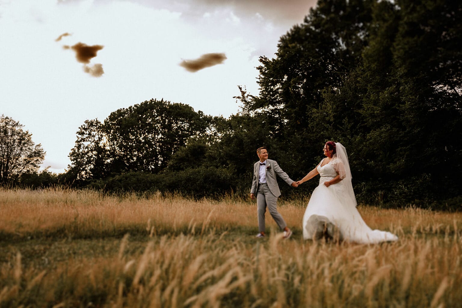 Schloss Oberhausen Empfang Nappenfeld Hochzeitsfotograf - Brautpaar bei Sonnenuntergang laufen Hand in Hand über Feld