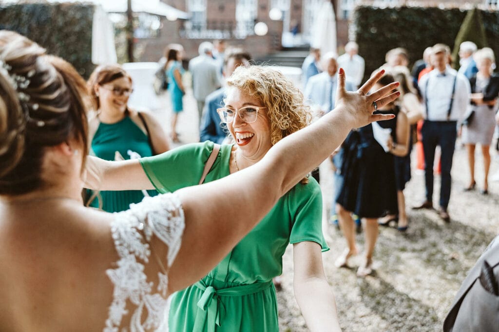 Schlosskapelle Diersfordt Wesel Schloss Diersfordt Wesel Hochzeitsfotograf - Frau in Grün breitet Hände aus, um Braut zu gratulieren