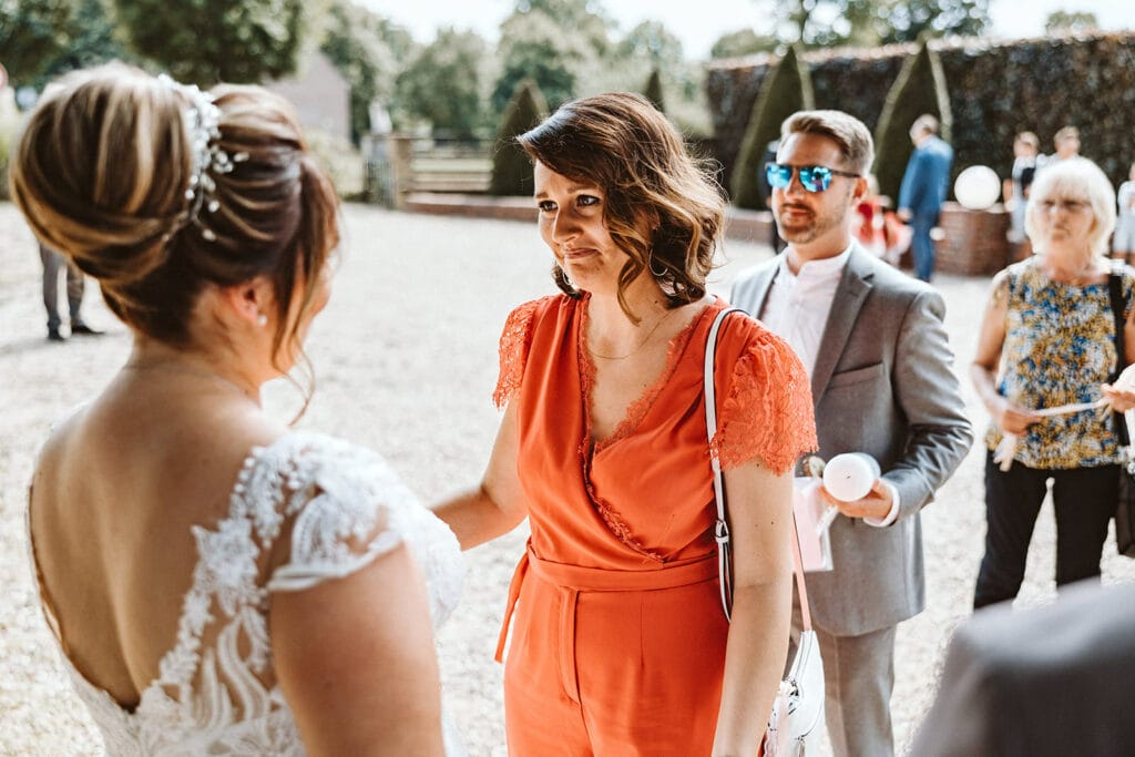 Schlosskapelle Diersfordt Wesel Schloss Diersfordt Wesel Hochzeitsfotograf - Trauzeugin in Orange gratuliert Braut zur Trauung
