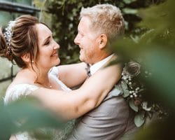 Schlosskapelle Diersfordt Wesel Schloss Diersfordt Wesel Hochzeitsfotograf - Brautpaar zwischen grünem Laub umarmen sich