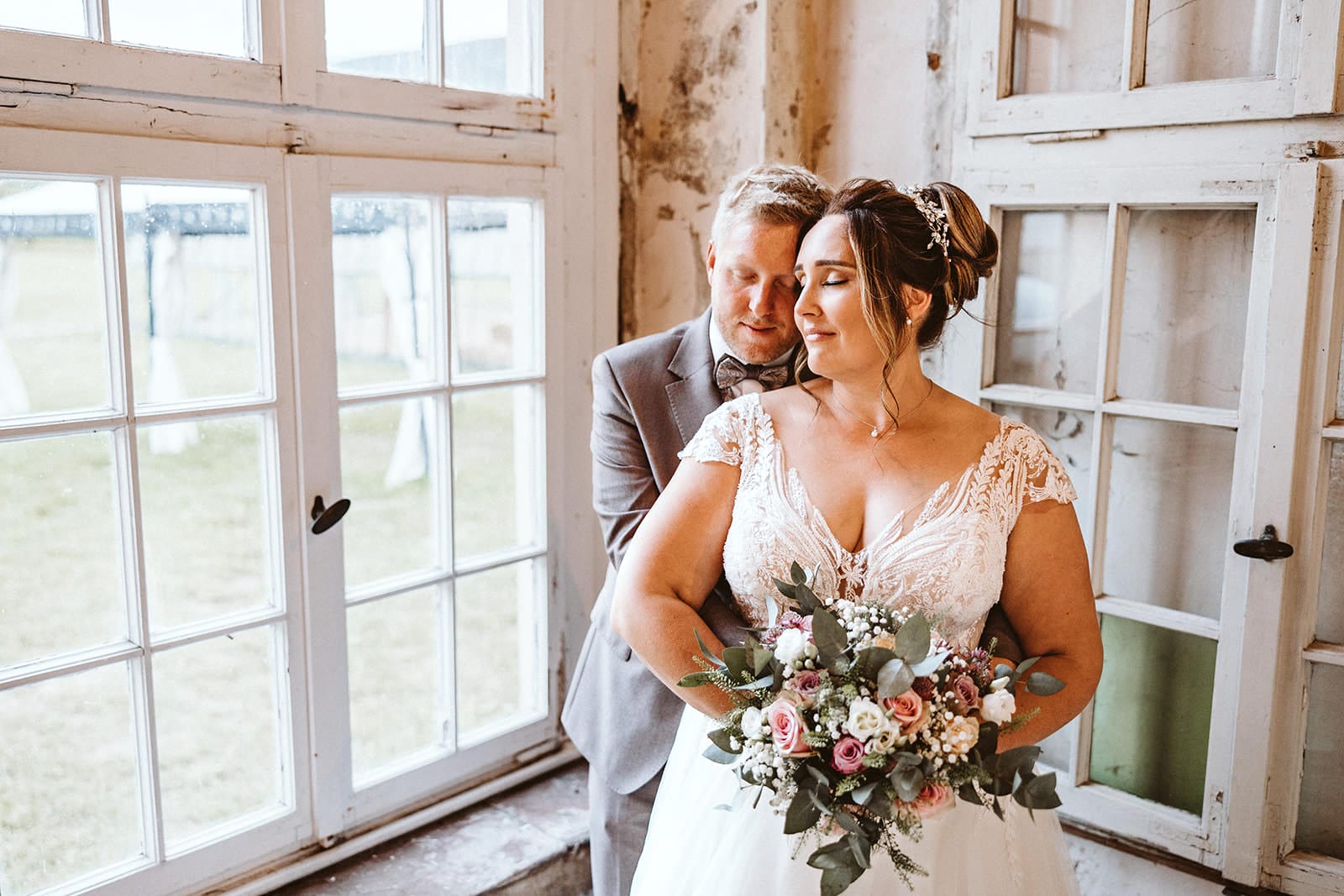 Schlosskapelle Diersfordt Wesel Schloss Diersfordt Wesel Hochzeitsfotograf - Brautpaar umarmt sich vor einem großen Fenster