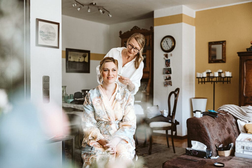 St. Mariä Empfängnis Essen Hochzeitsfotograf - Visagistin richtet Braut zurecht beim Getting Ready