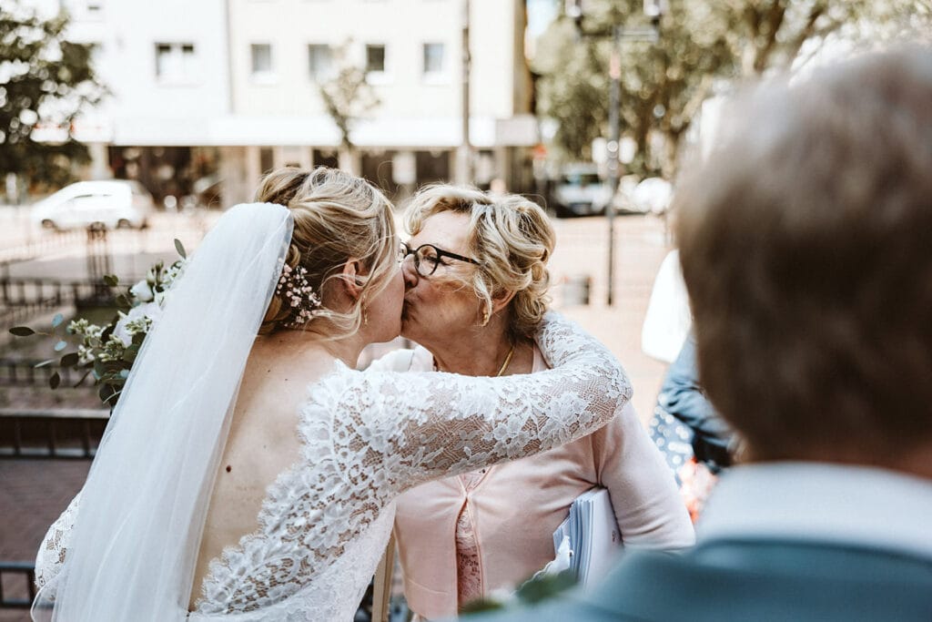 St. Mariä Empfängnis Essen Hochzeitsfotograf - Brautmutter gibt ihrer Tochter Braut einen Kuss auf die Wange