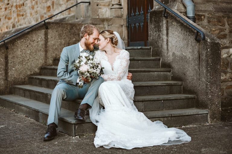 St. Mariä Empfängnis Essen Hochzeitsfotograf - Brautpaar Braut Bräutigam sitzt auf Treppe der Kirche