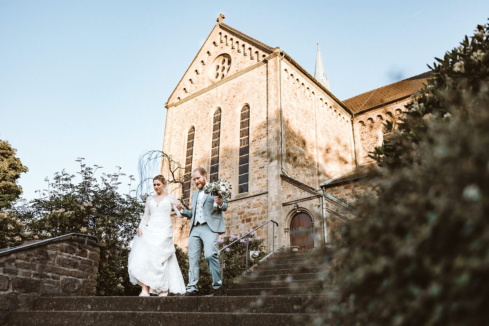 St. Mariä Empfängnis Essen Hochzeitsfotograf - Brautpaar läuft die Treppen der Kirche herunter