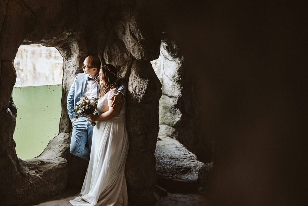 ZOOM Erlebniswelt Gelsenkirchen Ryokan Gelsenkirchen Hochzeitsfotograf - Braut und Bräutigam Arm in Arm in einer Höhle. Sie schauen aus einem Fenster