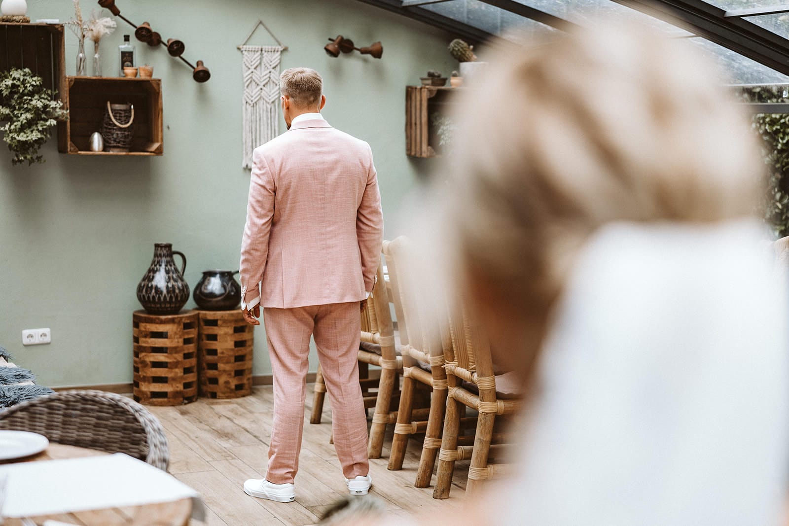 Die Farm Essen die Straußenfarm Essen Hochzeitsfotograf - First Look zwischen Braut und Bräutigam. Braut steht noch entfernt von Bräutigam im rosa Anzug