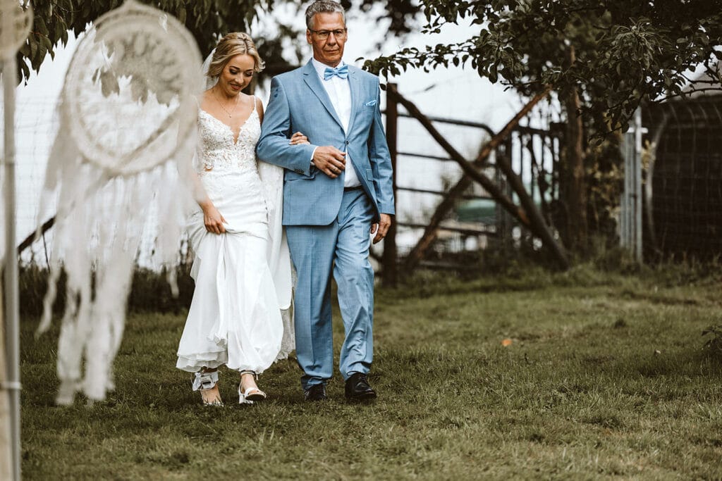 Die Farm Essen die Straußenfarm Essen Hochzeitsfotograf - Brautvater und Braut auf dem Weg zur freien Trauung, Hand in Hand