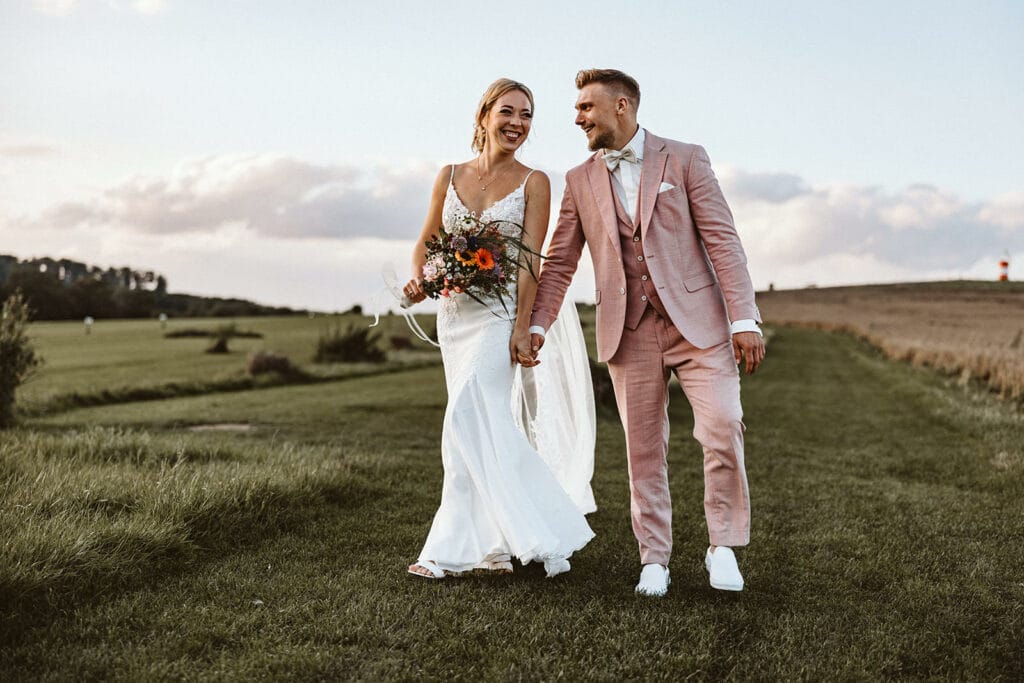 Die Farm Essen die Straußenfarm Essen Hochzeitsfotograf - Braut und Bräutigam halten Händchen auf grüner Wiese