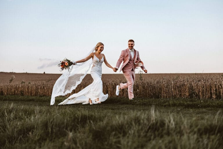 Die Farm Essen die Straußenfarm Essen Hochzeitsfotograf - Braut und Bräutigam rennen Hand in Hand über Feld