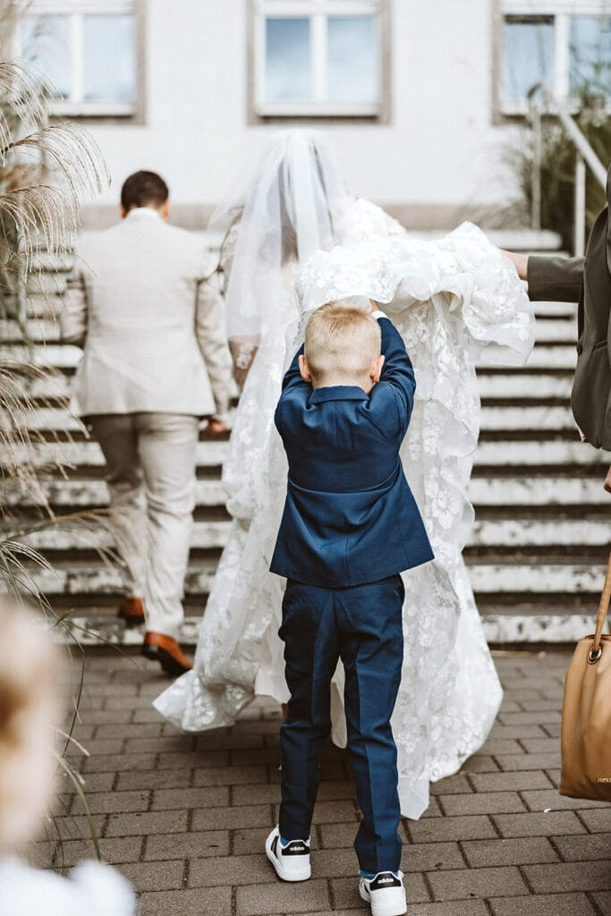 St. Marien Witten Hochzeitsfotograf - Kind trägt Schleier der Braut die Treppen rauf