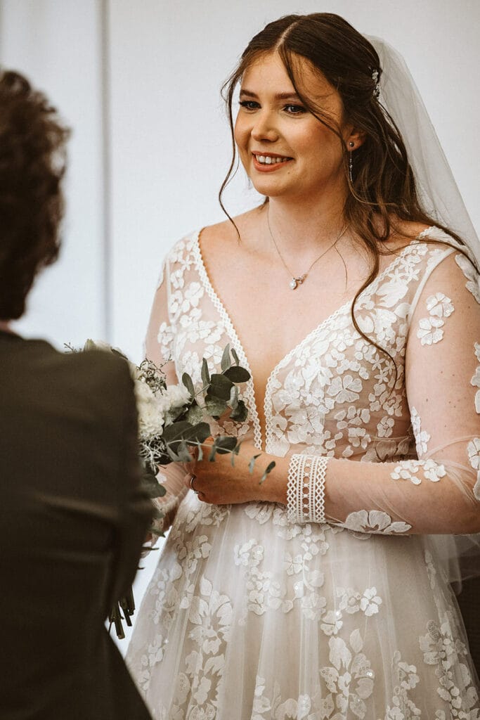 St. Marien Witten Hochzeitsfotograf - Braut hält kleinen Brautstrauß fest und redet mit Hochzeitsgast