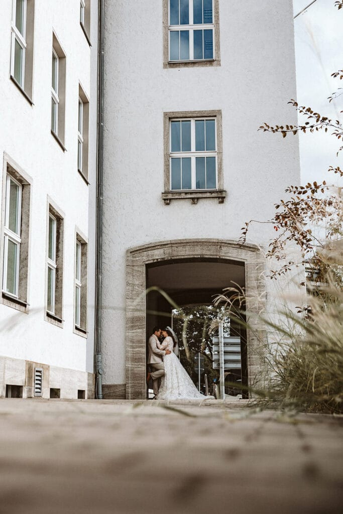 St. Marien Witten Hochzeitsfotograf - Weitwinkel-Perspektive von Braut und Bräutigam unter einem Vorsprung Turm
