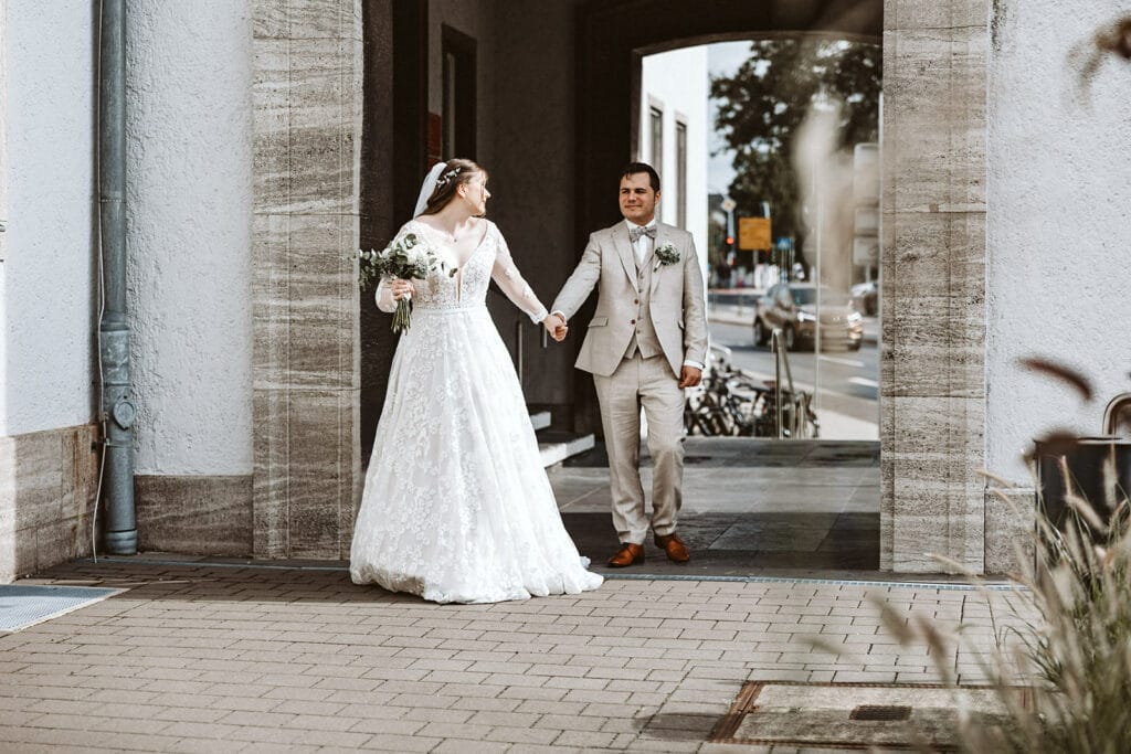 St. Marien Witten Hochzeitsfotograf - Braut und Bräutigam gehen Hand in Hand Stadt entlang