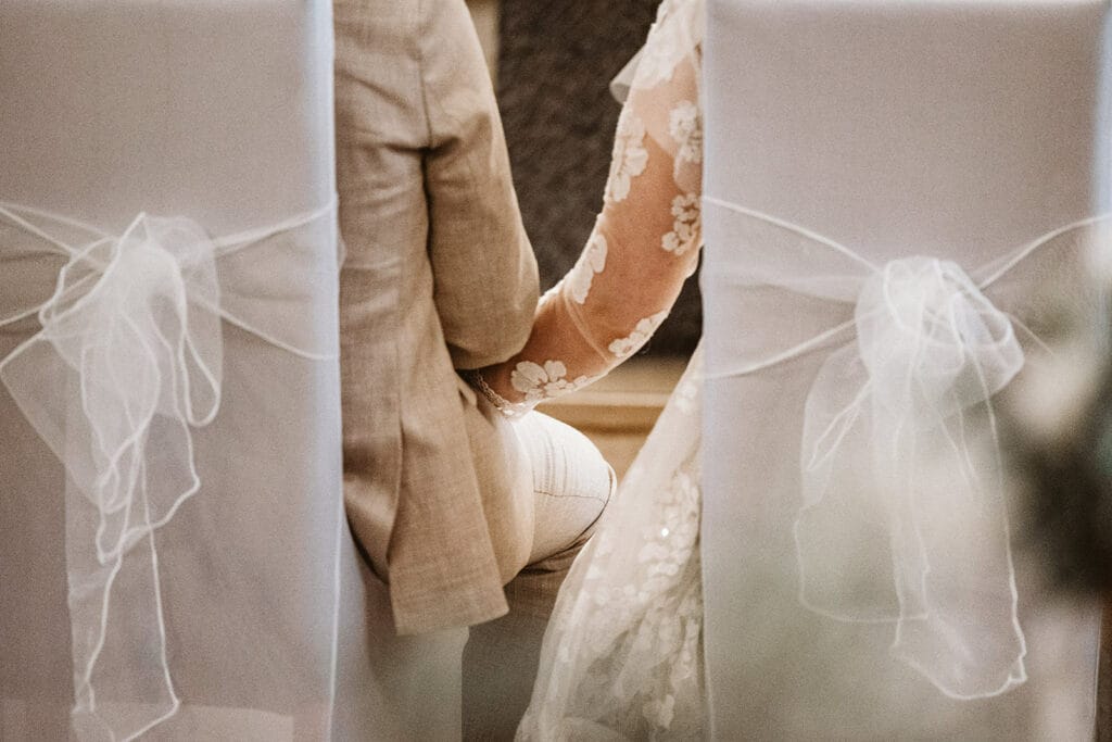 St. Marien Witten Hochzeitsfotograf - Braut und Bräutigam halten während katholischer Zeremonie in der Kirche die Hände