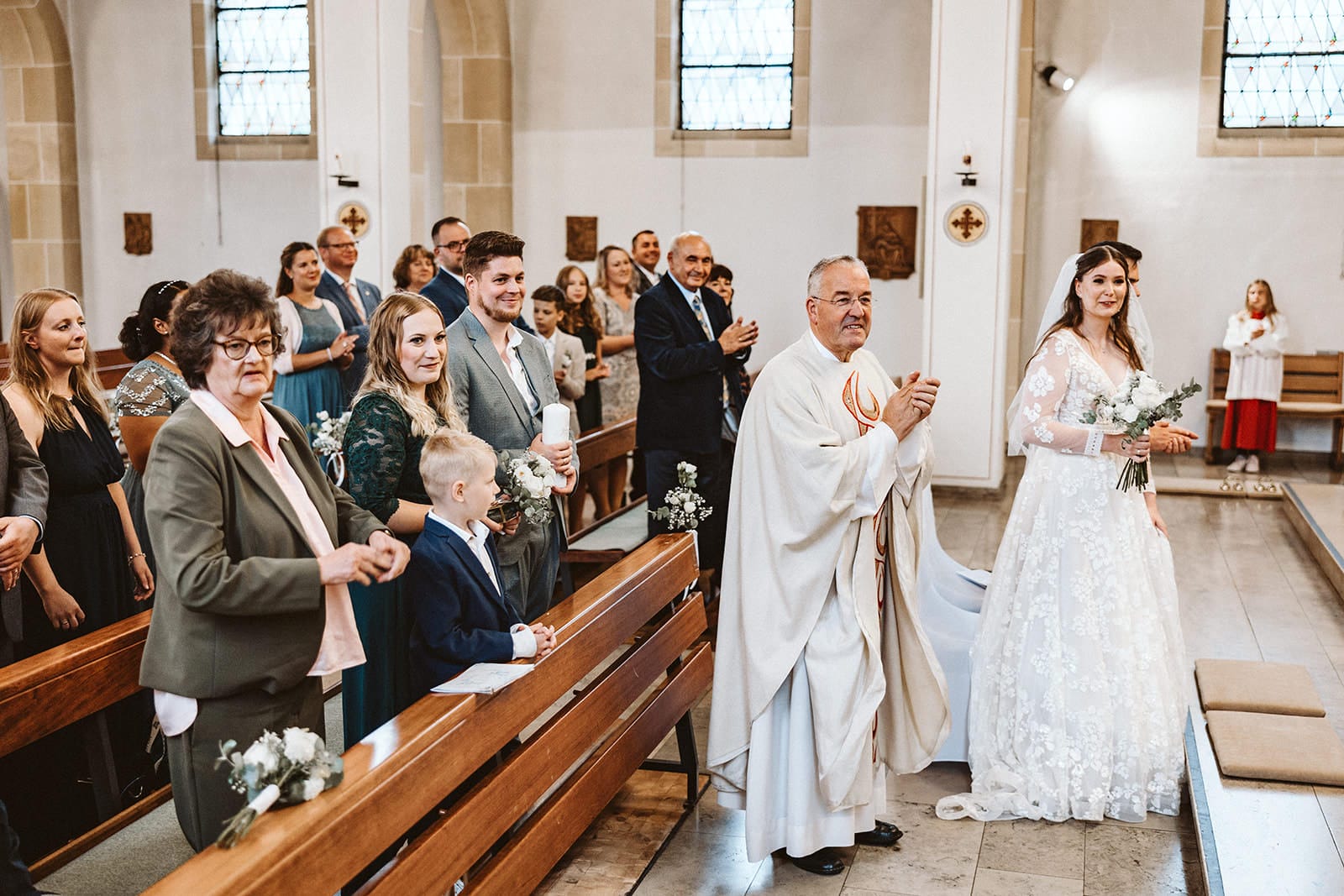 St. Marien Witten Hochzeitsfotograf - Priester und Braut sowie Hochzeitsgesellschaft klatschen zur Musik