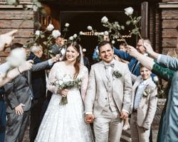 St. Marien Witten Hochzeitsfotograf - Auszug von Braut und Bräutigam Brautpaar aus der Kirche Spalier weiße Rosen