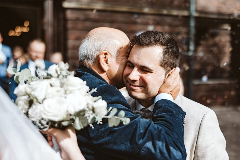 St. Marien Witten Hochzeitsfotograf - Trauvater geht zu Bräutigam und spricht seinen Glückwunsch zur Ehe aus
