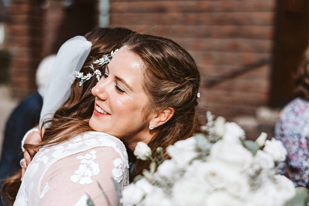 St. Marien Witten Hochzeitsfotograf - weiblicher Hochzeitsgast umarmt Braut nach Zeremonie