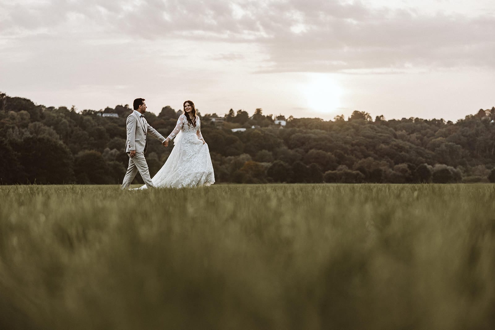 St. Marien Witten Hochzeitsfotograf - After Wedding Session von Braut und Bräutigam Sonnenuntergang Hand in Hand über einem Feld