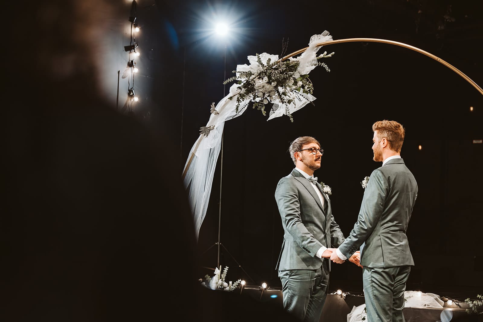 Theater Narrenschiff Unna Lindenbrauerei Kühlschiff Unna Hochzeitsfotograf - Unter dem Traubogen steht ein schwules homosexuelles gleichgeschlechtliches Ehepaar und hält sich in grünen Anzügen die Hände