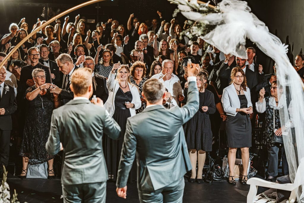 Theater Narrenschiff Unna Lindenbrauerei Kühlschiff Unna Hochzeitsfotograf - schwules homosexuelles gleichgeschlechtliches Ehepaar gibt einen Toast zu den Hochzeitsgästen nach Trauung