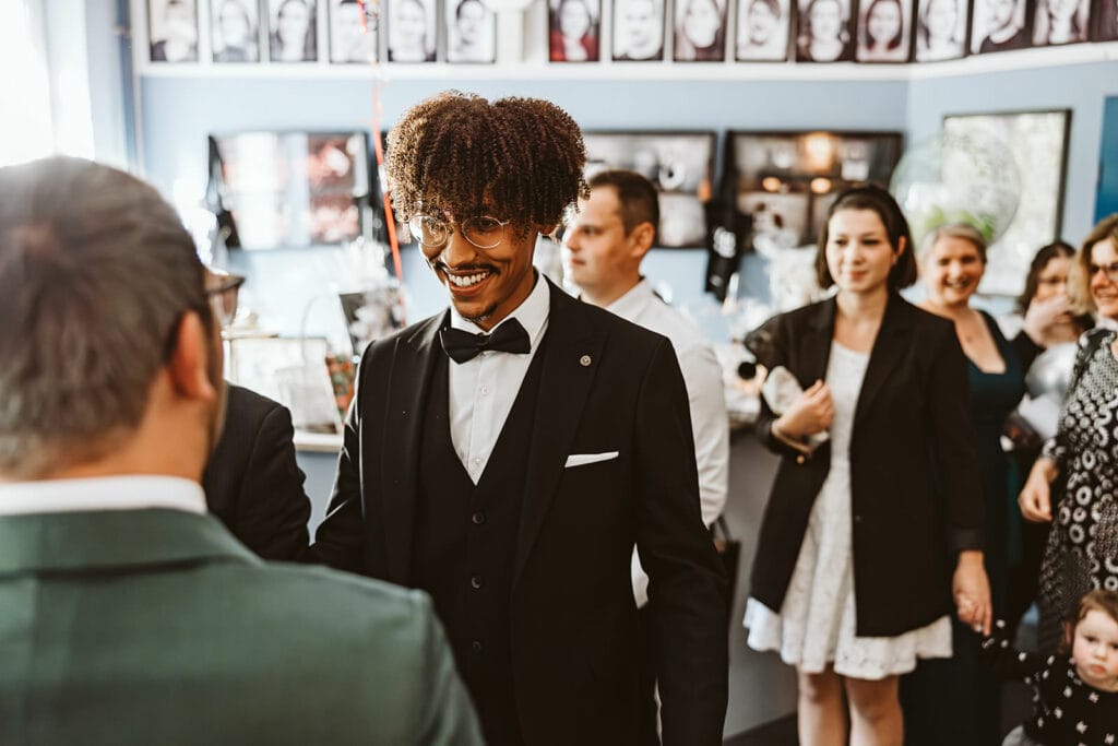 Theater Narrenschiff Unna Lindenbrauerei Kühlschiff Unna Hochzeitsfotograf - Mann gratuliert Hochzeitspaar im schwarzen Anzug zur Ehe