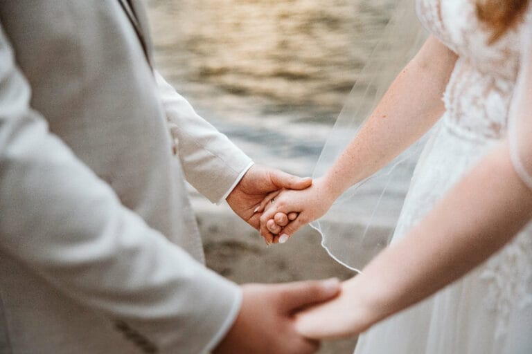 Hochzeit Heiraten Hochzeitsfotograf Dominik Neugebauer - Braut und Bräutigam halten sich am Strand beide Hände.