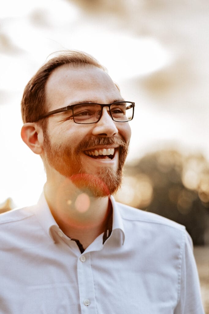 Hochzeit Heiraten Hochzeitsfotograf Dominik Neugebauer - Der Fotograf schaut nach rechts und lächelt, während des Sonnenuntergangs