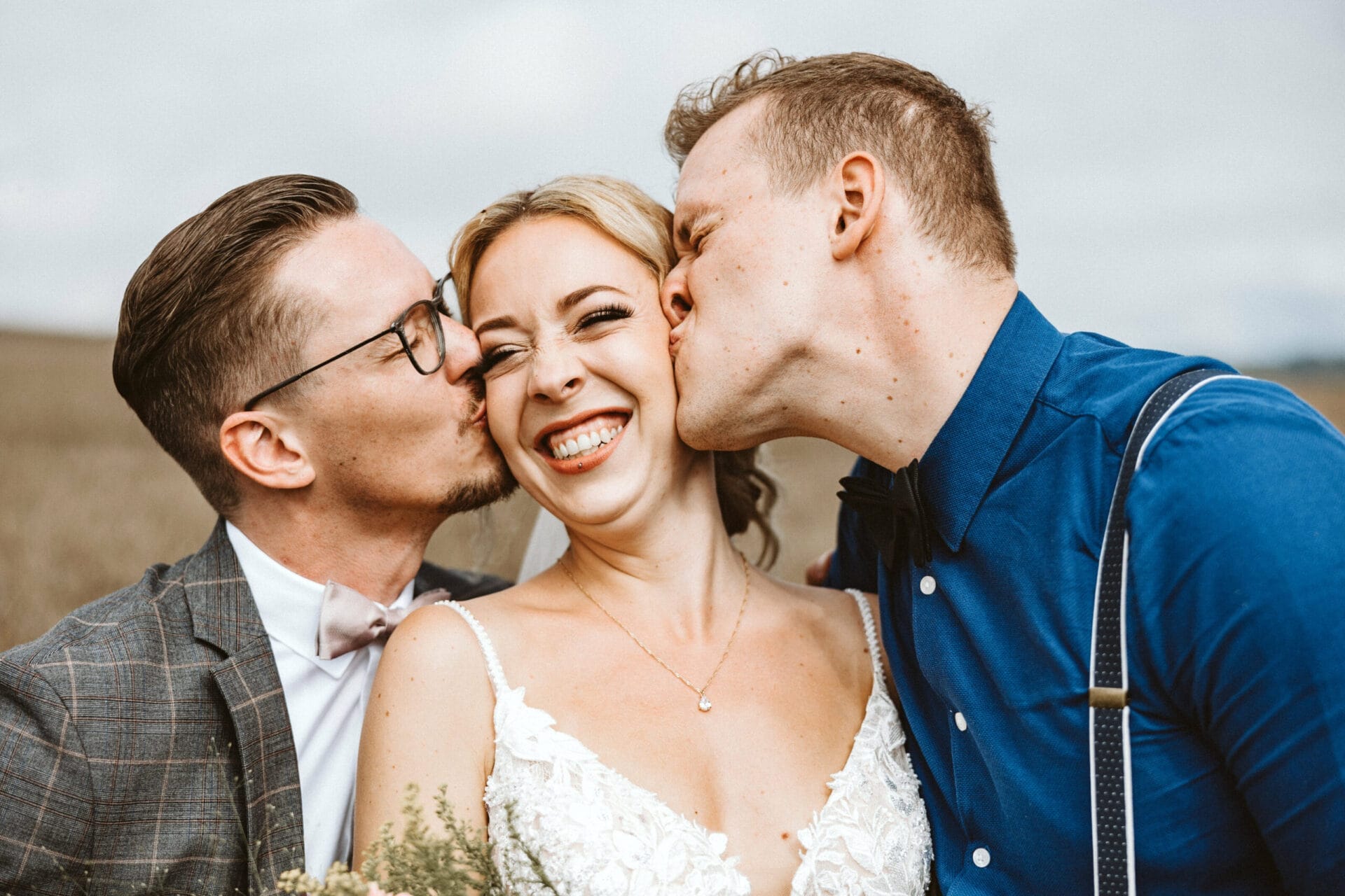 Hochzeit Heiraten Hochzeitsfotograf Dominik Neugebauer - Braut wird von Trauzeuge und Bräutigam auf die Wange geküsst. Die Braut lächelt.