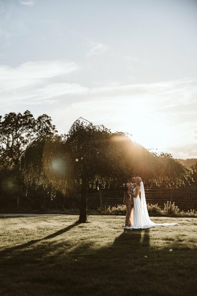 Hochzeit Heiraten Hochzeitsfotograf Dominik Neugebauer - Brautpaar küsst sich unter einem Baum bei Sonnenuntergang