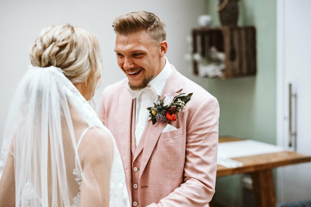 Hochzeit Heiraten Hochzeitsfotograf Dominik Neugebauer - Bräutigam mit rosarotem Anzug sieht seine Braut beim First Look zum ersten Mal.