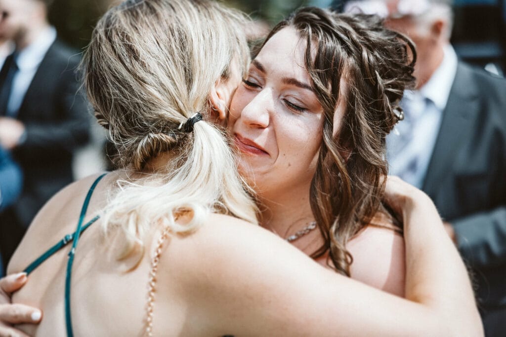 Hochzeit Heiraten Hochzeitsfotograf Dominik Neugebauer - Die Braut umarmt einen Hochzeitsgast und fängt fast das Weinen an. Sie ist den Tränen nahe.