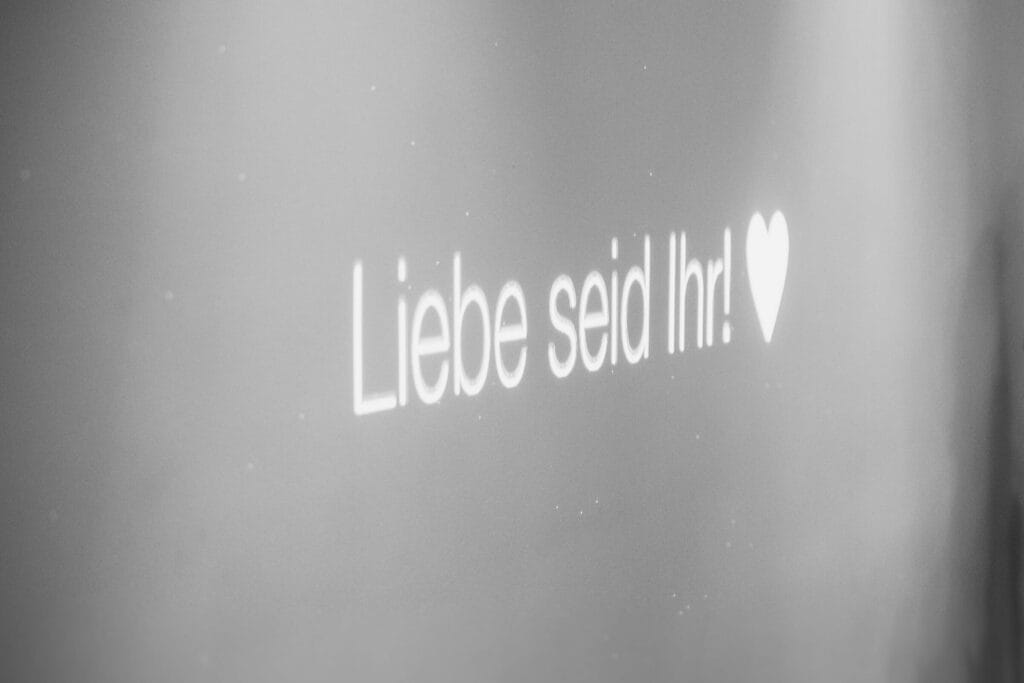 Hochzeit Heiraten Hochzeitsfotograf Dominik Neugebauer - Mit dem Beamer ist auf der Hochzeitsparty die Schrift "Liebe seid Ihr!" und einem Herzchen-Icon zu sehen.
