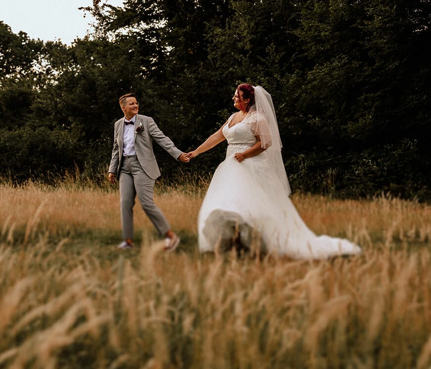 Hochzeit Heiraten Hochzeitsfotograf Dominik Neugebauer Portfolio - Hochzeitspaar läuft Hand in Hand auf einem Feld entlang