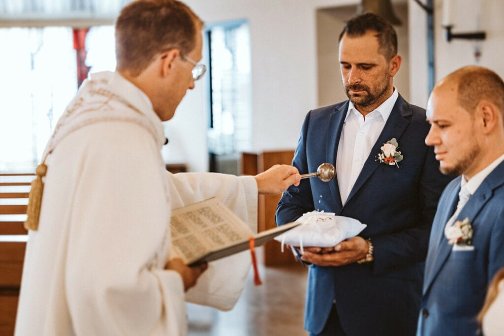 St. Marien Kirche Schloss Diersfordt Hochzeitsfotograf - Weihwasser des Priesters der Kirche